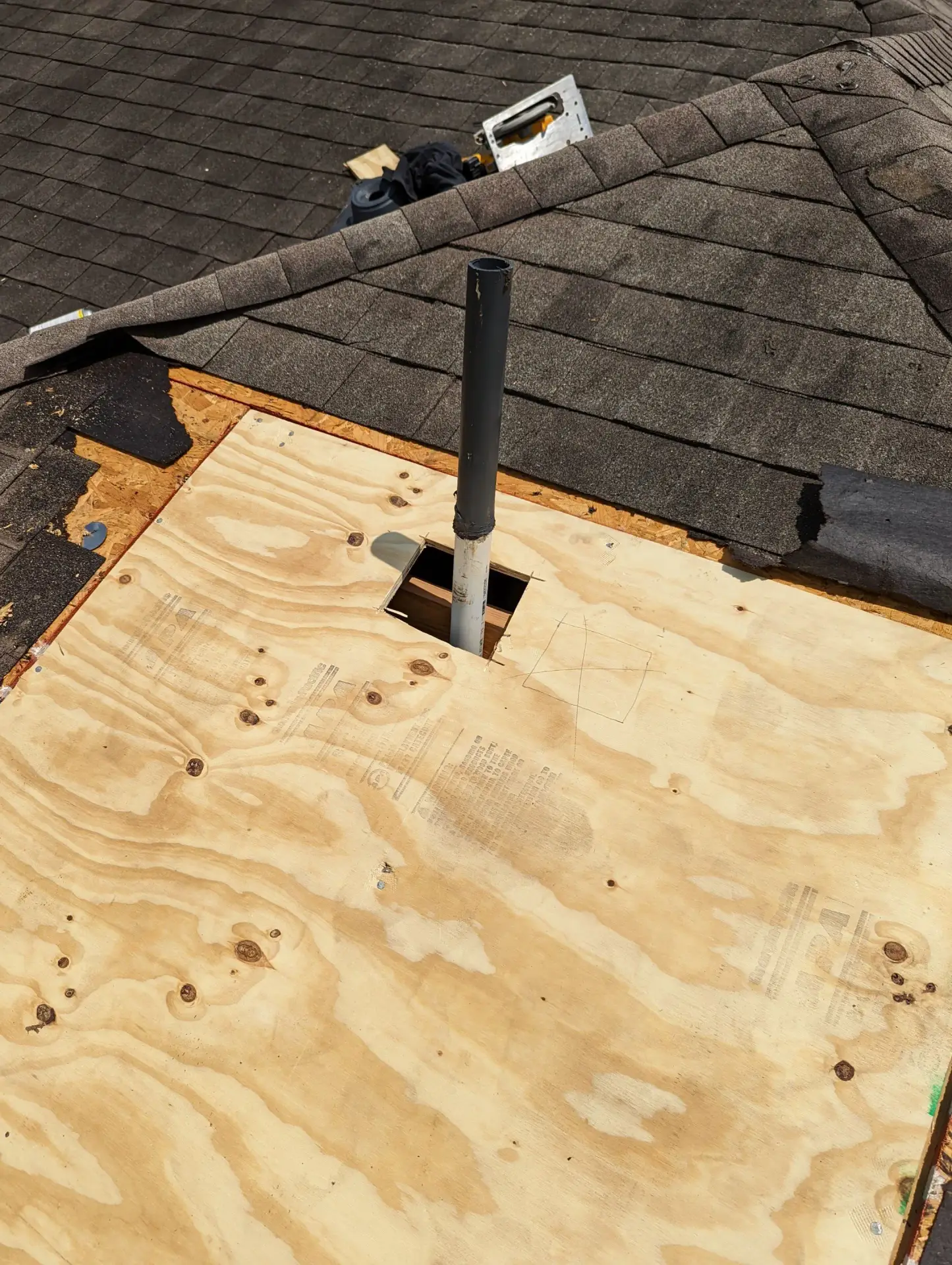Shingle roof opened to the decking around a vent pipe during a commercial repair