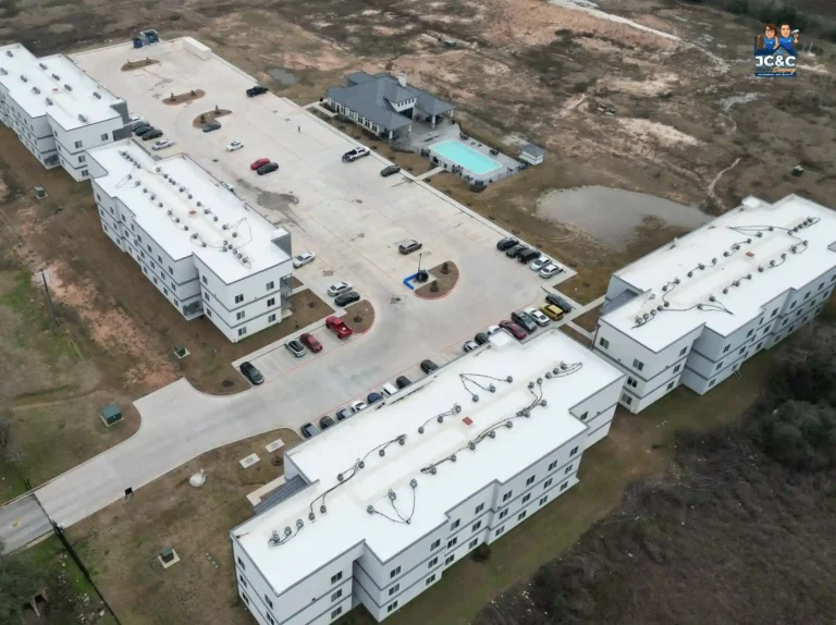Drone view of a multi-building student housing complex with white TPO low-slope roofs
