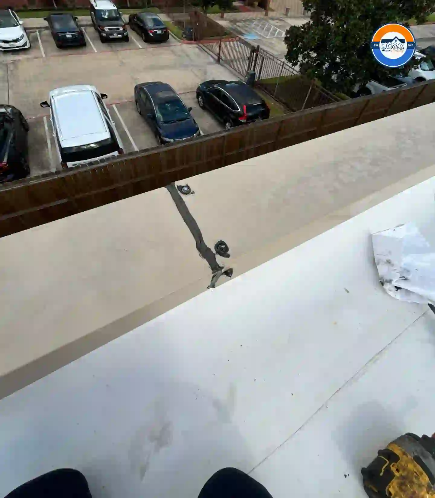 Roofer sealing the metal coping on a parapet wall above a TPO roof
